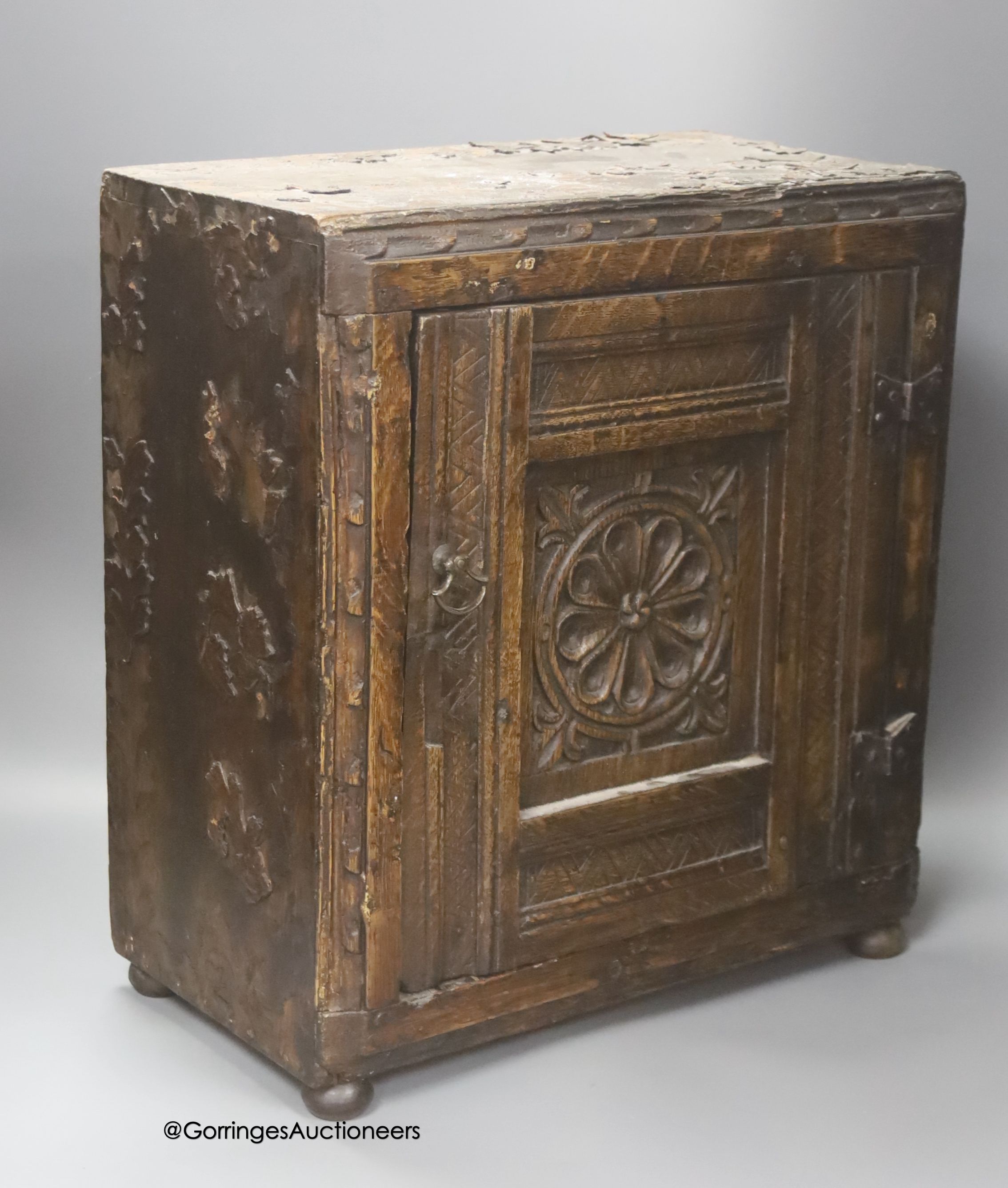 A small 17th century carved oak wall cabinet, enclosed by single panelled door with iron butterfly hinges, width 37cm